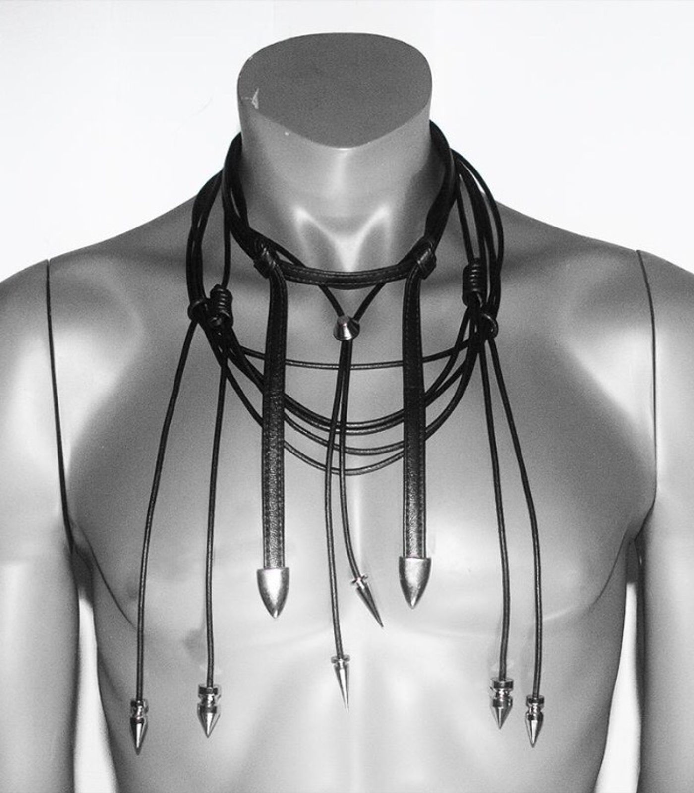 Layered black leather bolo with silver tips on a form