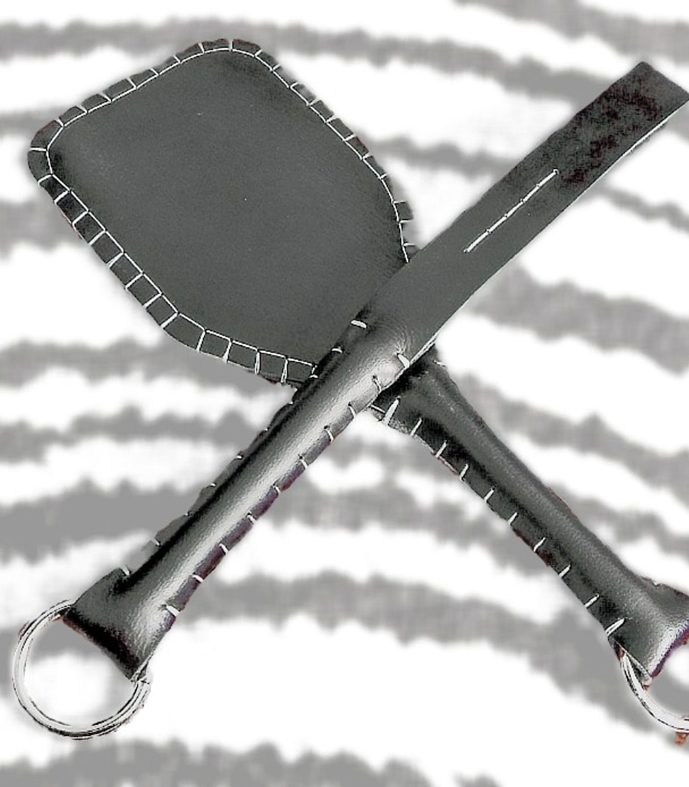 Black leather strap and paddle with white stitching, crossed